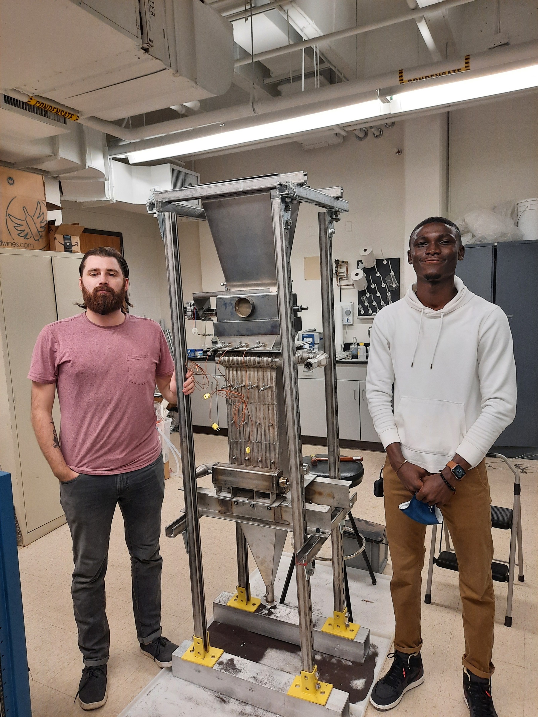 Winfred Arthur-Arhin and colleague standing beside a laboratory heat-transfer rig