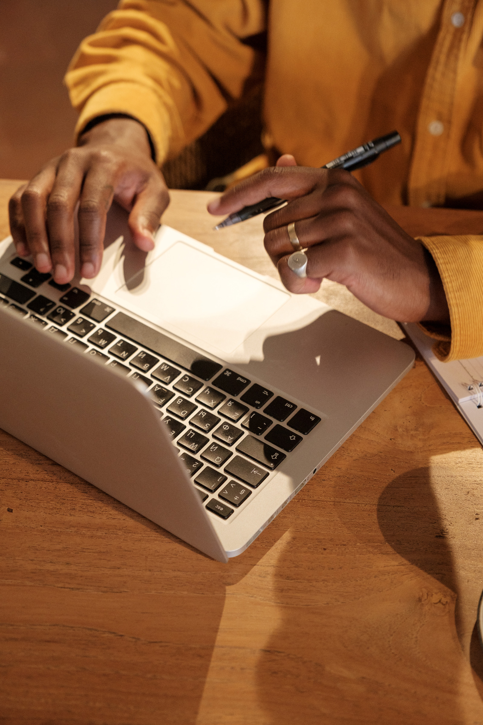 Close-up of hands writing next to a laptop